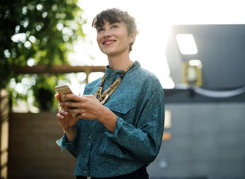 Une entrepreneuse souriante, téléphone en main