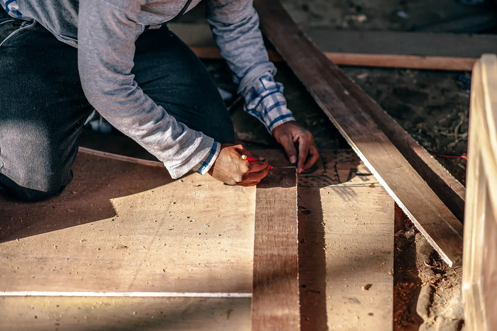 Un menuisier trace sa coupe sur une planche